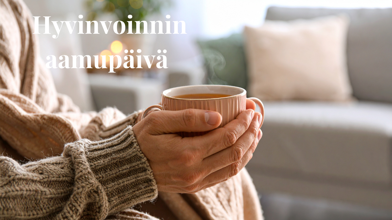 Nainen beigessä villapaidassa pitelee käsissään kupillista lämmintä juomaa, taustalla harmaa sohva.